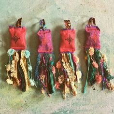 three small handmade dolls hanging on a wall