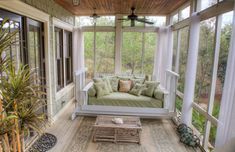 an enclosed porch with couches and potted plants