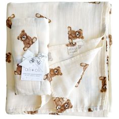 a white blanket with brown teddy bears on it and a tag hanging from the bottom