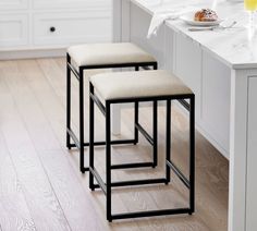 three stools sitting on top of a wooden floor next to a white kitchen counter