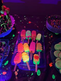 a table topped with cake pops covered in neon colored frosting