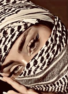 a close up of a person with a scarf on their head and eyes covered by a blanket