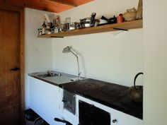 an old fashioned stove with pots and pans on the shelf above it in a kitchen