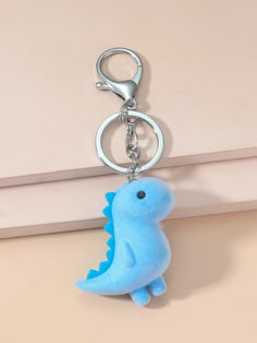 a blue dinosaur keychain hanging from a hook