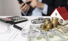 a person holding a cell phone next to stacks of money and a calculator