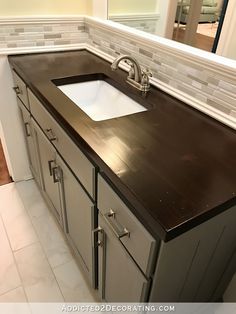 a bathroom sink sitting under a mirror next to a counter top with drawers underneath it