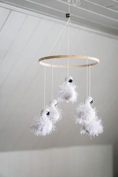 three white fluffy balls hanging from a circular chandelier