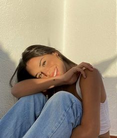 a woman is sitting on the floor with her arms crossed and smiling at the camera