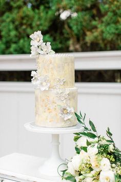 a wedding cake sitting on top of a table next to white flowers and greenery