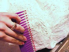 a woman is holding a purple comb in her left hand and wearing a wedding ring