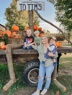 a woman and two boys posing in front of a truck with pumpkins