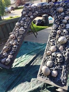 there are many skulls and bones on the ground in front of a large letter that is made out of cement