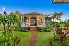 a house that is in the middle of some plants and grass with a walkway leading to it