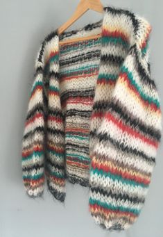 a multicolored sweater hanging on a wooden hanger