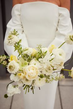 a bride holding a bouquet of white and yellow flowers