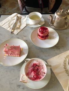 three plates with desserts on them sitting on a table next to a tea pot