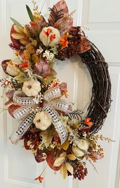 a wreath with fall leaves and flowers hanging on the front door to welcome someone in their home