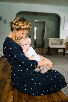 a woman sitting on the floor holding a baby