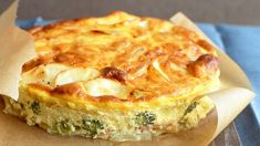 a quiche with cheese and broccoli sitting on top of a piece of wax paper