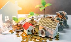 small model houses and coins on a table