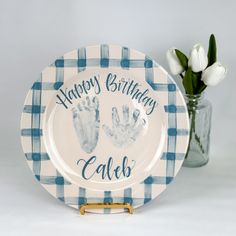 a blue and white plate that says happy birthday cales with two hand prints on it