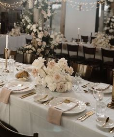 the table is set with white and gold plates, silverware, and flower centerpieces