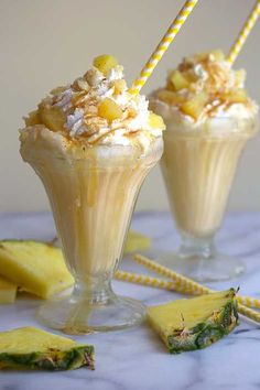 two glasses filled with ice cream next to sliced pineapple