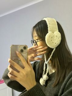 a woman taking a selfie with her cell phone wearing headphones and ear muffs