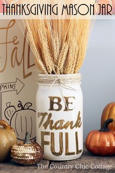 an arrangement of pumpkins, gourds and hay in a mason jar on a table