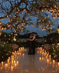 a man and woman standing under a tree covered in candles