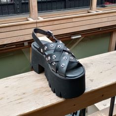 The Demonia Ashes-12 In Black Has A 3" Platform With Slight 3.75" Heel And Criss-Crossing Front Straps With Star Grommet Hardware, As Well As A Plain Black Adjustable Back Strap. #Demonia #Demoniaashes #Demoniaashes12 #Ashes12 #Platformsandal Spring High Heels With Silver Studs, Spring Silver Studded High Heels, Summer Party Sandals With Silver Studs, Spring Open Toe Sandals With Silver Studs, Black Open Toe Sandals With Silver Studs, Silver Platform Sandals In Synthetic Material, Summer Open Toe Sandals With Silver Studs, Black Sandals With Silver Studs For Summer, Silver Open Toe Sandals With Studded Rubber Outsoles