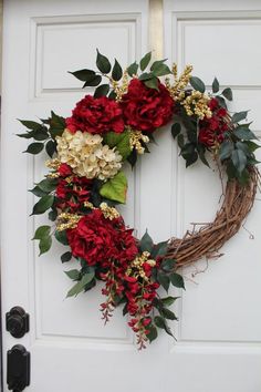 a wreath with red flowers and greenery hangs on the front door