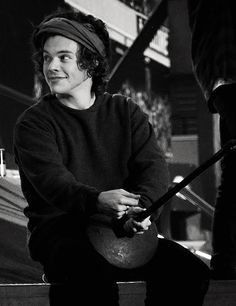 a black and white photo of a man sitting on the steps with a guitar in his hand