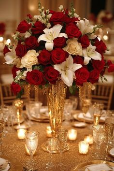 a vase filled with red roses and white lilies on top of a gold table