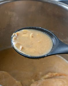 a ladle full of soup is being held by a wooden spoon in a pot