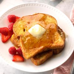 french toast with butter and strawberries on a white plate