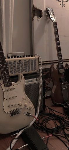 two electric guitars sitting on top of a hard wood floor next to a speaker and amp