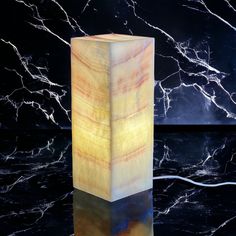 a tall wooden block sitting on top of a black table next to a marble wall