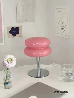 a pink lamp sitting on top of a white table next to a vase filled with flowers