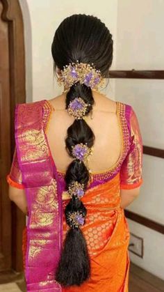 a woman in an orange and pink sari with two braids on her head