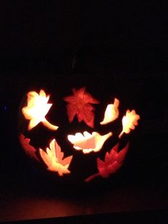 a lit up pumpkin with leaves on it