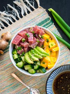 a bowl filled with meat and veggies next to a cup of soup on a table