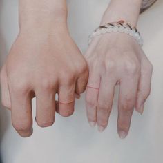 two hands holding each other with one hand on the other's wrist, both wearing beaded bracelets