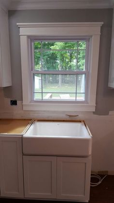 an empty kitchen with white cabinets and a window above the sink that has no curtains on it