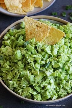 a bowl filled with guacamole and tortilla chips on the side