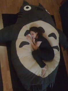 a woman laying on top of a pillow shaped like a totoro