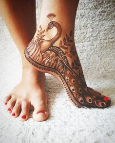 a woman's foot with a peacock tattoo on it