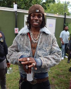 a man with dreadlocks is holding a bottle in his hand and wearing a hat