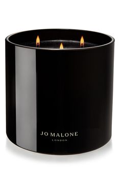 a black candle holder with two lit candles in the center and jo malone logo on it