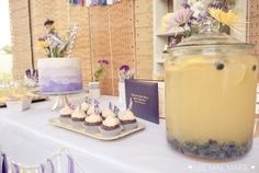 a table topped with cupcakes and cakes next to a jar filled with frosting